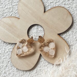 Boucles d'oreilles en forme de cœur en résine avec des fleurs séchées incrustées et attaches en acier inoxydable.