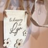 Pancarte en bois personnalisable avec fleurs et paillettes, accrochée par un ruban délicat pour une décoration murale douce et naturelle.