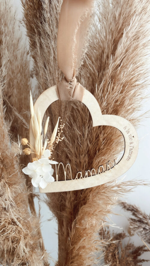 Suspension en bois en forme de cœur avec l'inscription 'À la vie à l'amour' et des fleurs séchées, ornée d'un ruban beige.