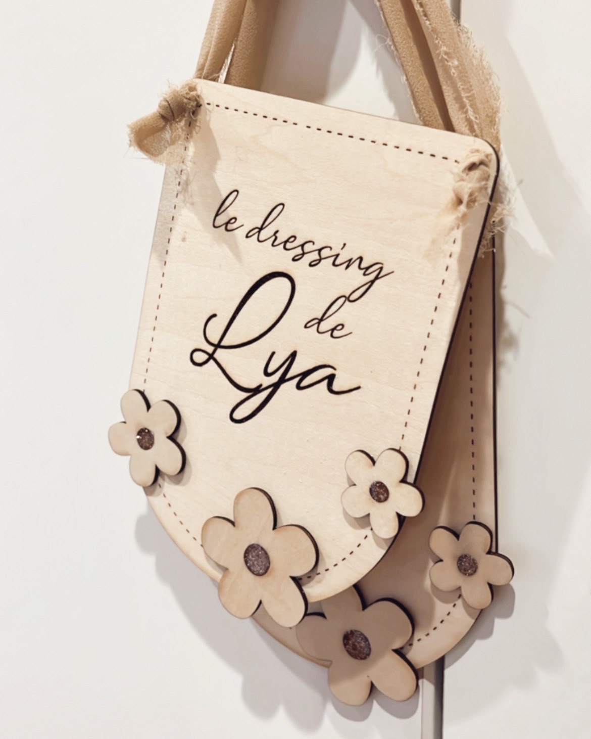 Pancarte en bois personnalisable avec fleurs et paillettes, accrochée par un ruban délicat pour une décoration murale douce et naturelle.