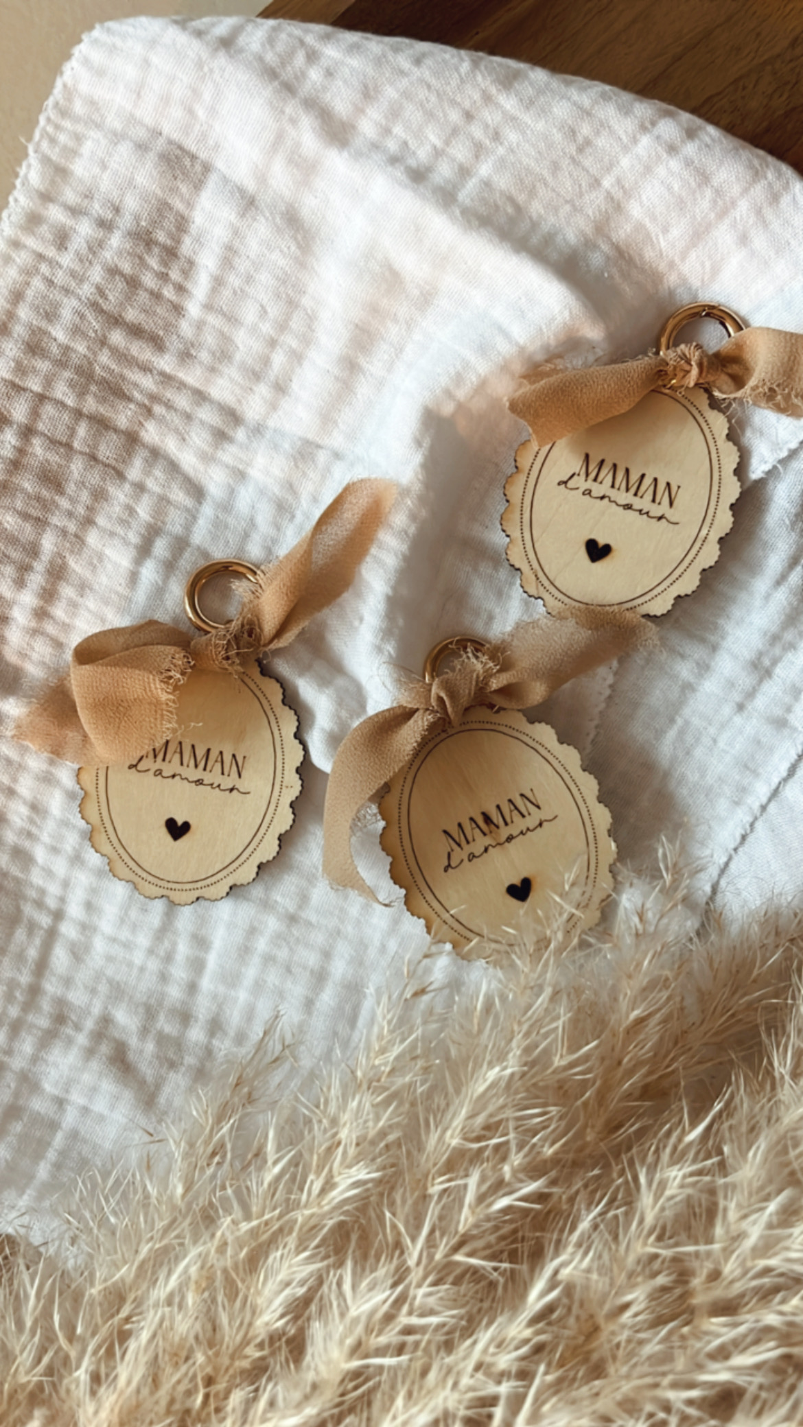 Porte-clés en bois gravé avec l'inscription 'Maman d'Amour', orné d'un ruban beige et d'un petit cœur.