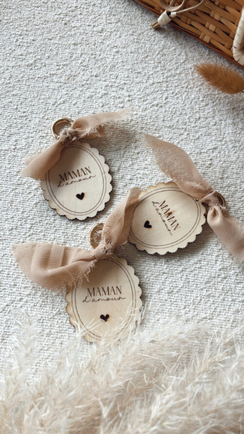 Porte-clés en bois gravé avec l'inscription 'Maman d'Amour', orné d'un ruban beige et d'un petit cœur. Cadeau fête des mères.