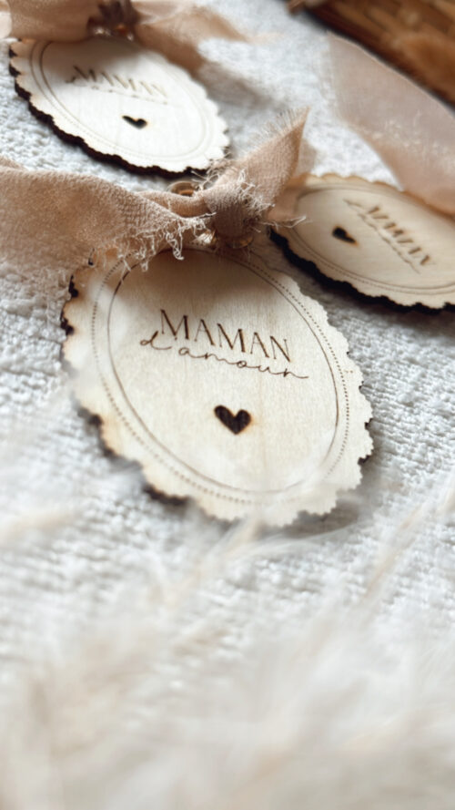 Porte-clés en bois gravé avec l'inscription 'Maman d'Amour', orné d'un ruban beige et d'un petit cœur. Cadeau fête des mères.