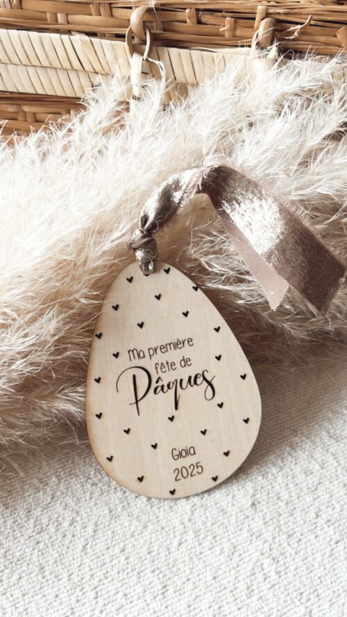 Médaillon décoratif en bois gravé 'Ma première fête de Pâques' avec personnalisation orné d'un ruban doré.