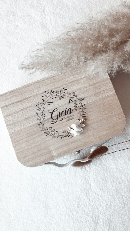 Valisette "Mes Premiers Souvenirs" en bois naturel, finement gravée avec le nom de bébé et ornée de fleurs séchées. Cette boîte à souvenirs est parfaite pour conserver les premiers moments précieux de bébé. Idéale comme cadeau de naissance personnalisé, elle allie élégance et sentimentalité.