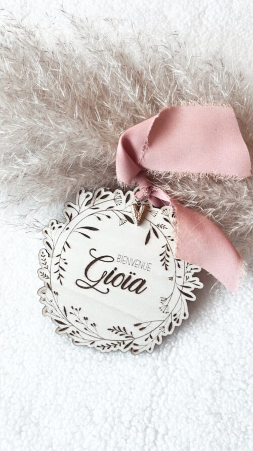 Médaillon bienvenue bébé en bois naturel, finement gravé avec le nom de bébé et orné d'un ruban délicat et de son petit coeur. Ce médaillon est parfait comme cadeau de naissance personnalisé ou comme décoration pour la chambre de bébé. Chaque pièce est unique et artisanale, idéale pour un souvenir de naissance spécial et plein d'amour.
