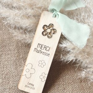 Marque-page en bois gravé 'Merci Maîtresse' avec un ruban vert menthe, des fleurs gravées et le prénom de l'enfant et avec l'année scolaire.