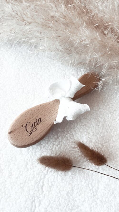 Brosse pour bébé en bois naturel, finement gravée avec le nom de bébé. Parfaite comme cadeau de naissance unique et plein d'amour, cette brosse bébé artisanale est ornée d'un nœud blanc délicat. Idéale pour les soins délicats de votre nouveau-né, elle allie élégance et praticité.
