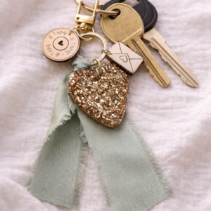 Porte-clé cœur pailleté doré avec ruban délicat et breloques en bois, idée cadeau artisanale pour la Fête des Mères ou des Grands-Mères.